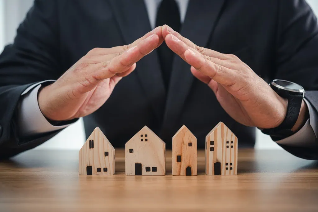 asset protection concept with man covering homes with his hands